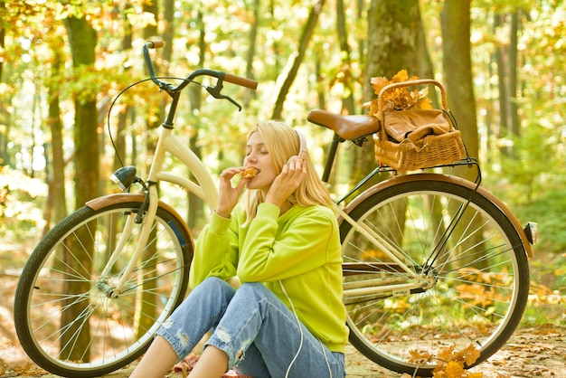 Hermosa mujer de otoño haciendo un picnic en un bosque de otoño sentado en el césped y comiendo caminata otoñal ...
