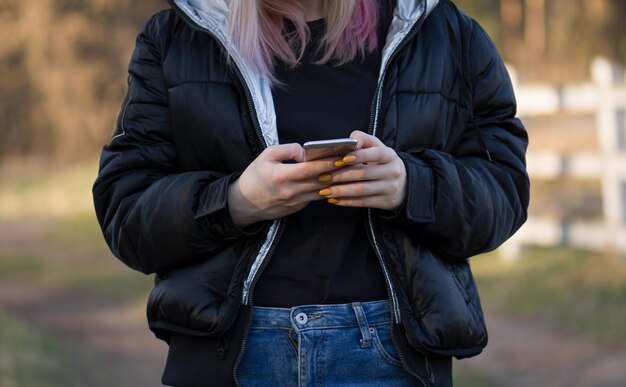 Hermosa mujer en paisaje otoñal Joven hipster sosteniendo teléfono móvil y mirando la pantalla Mujer con teléfono móvil Chica usando el teléfono celular cerca