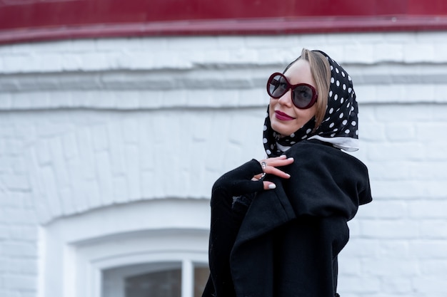 Hermosa mujer con pañuelo en la cabeza en estilo retro caminando por la calle