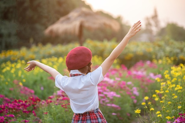 Una hermosa mujer parada en un jardín de flores por la noche y disfruta de la naturaleza