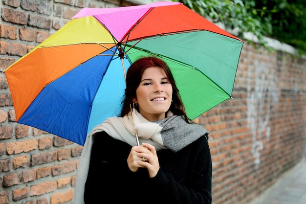 Hermosa mujer bajo paraguas de arco iris