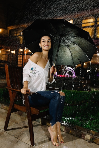 Hermosa mujer con el paraguas sentado en el banco