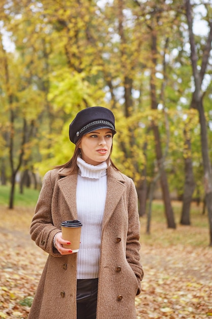 Hermosa mujer en el parque de otoño con café