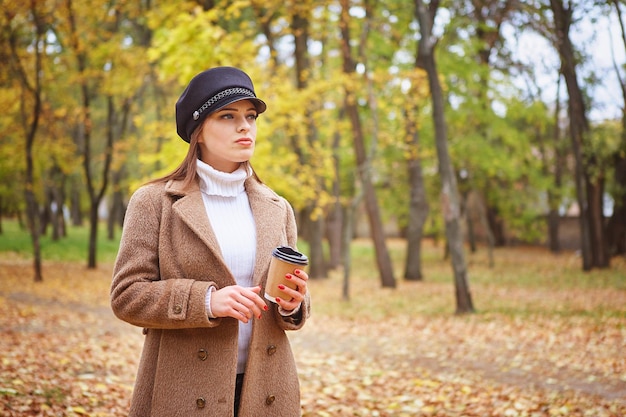 Hermosa mujer en el parque de otoño con café