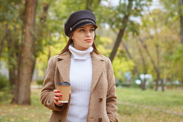 Hermosa mujer en el parque de otoño con café
