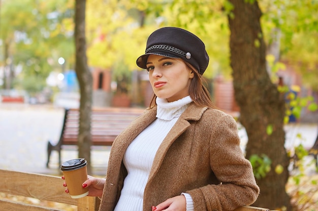 Hermosa mujer en el parque de otoño con café