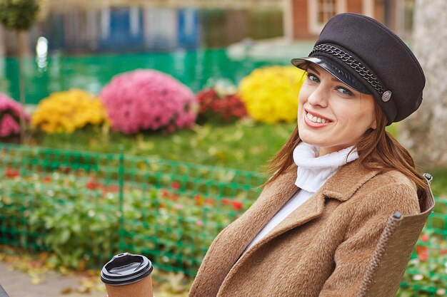 Hermosa mujer en el parque de otoño con café