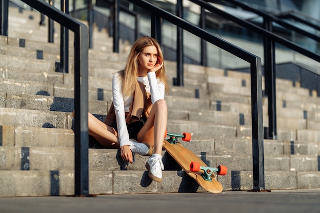 Hermosa mujer patina por la ciudad. Estilo de vida y vacaciones de verano. Foto de alta calidad