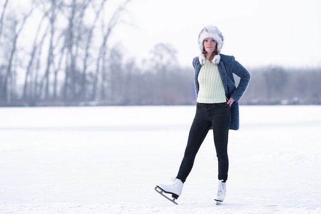 Hermosa mujer patinando en el lago congelado