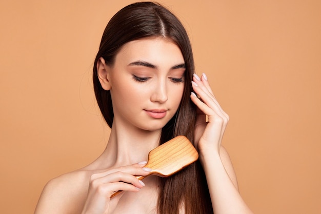 Hermosa mujer peina su cabello con cepillo de madera