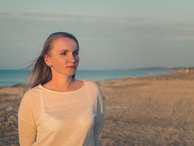 Hermosa mujer con pelo de vuelo en la playa de noche.