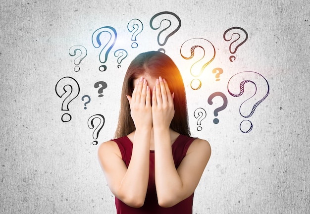 Hermosa mujer pensante con signos de interrogación