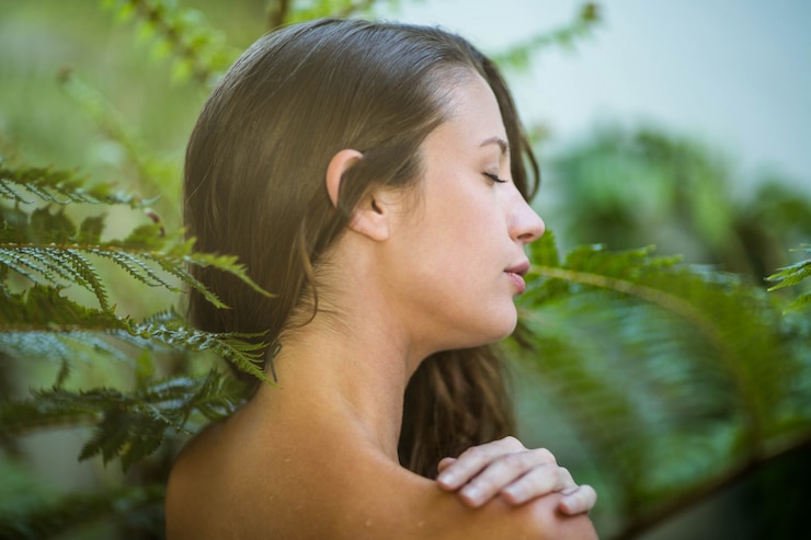 Foto hermosa mujer de pie al aire libre contra las plantas verdes
