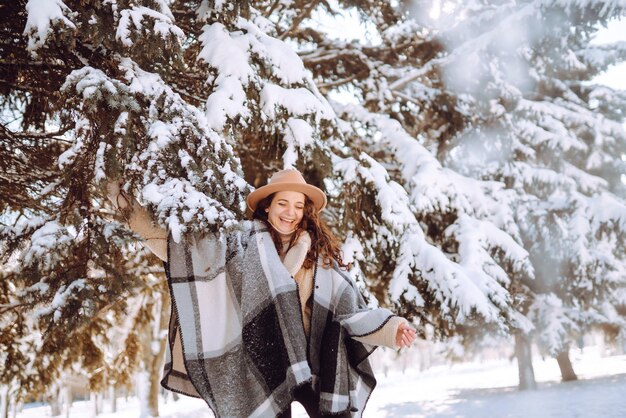 Hermosa mujer de pie entre árboles nevados y disfrutando de la primera nieve. Momento feliz. Navidad.