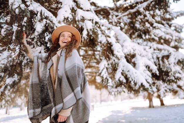 Hermosa mujer de pie entre árboles nevados y disfrutando de la primera nieve Tiempo feliz Navidad