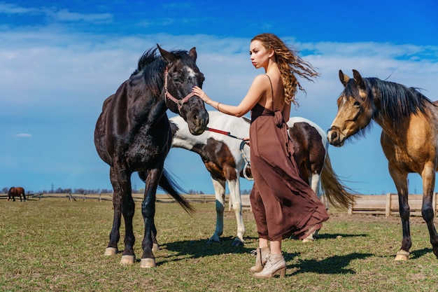 Hermosa mujer de pie en un campo con un caballo