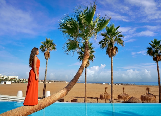 Hermosa mujer de pie en la palmera doblada