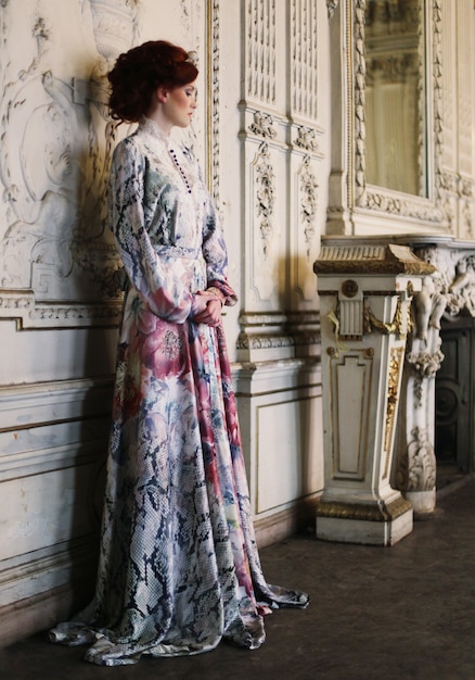 Foto hermosa mujer de pie en la sala del palacio.