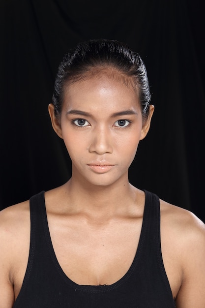 Hermosa mujer de piel bronceada de pelo negro recto largo asiático en vestido negro delgado, maquillaje de moda, espacio de copia aislada de fondo de tela oscura de iluminación de estudio