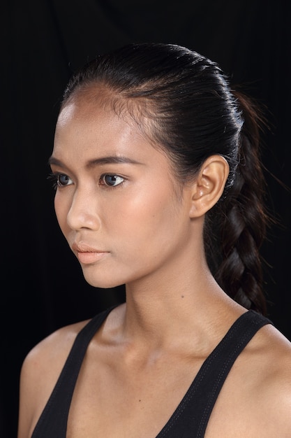 Hermosa mujer de piel bronceada de pelo negro recto largo asiático en vestido negro delgado, maquillaje de moda, espacio de copia aislada de fondo de tela oscura de iluminación de estudio