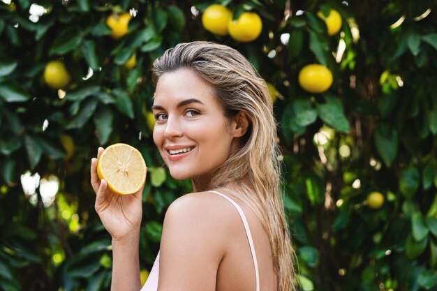 Hermosa mujer con piel suave con una fruta de limón en sus manos