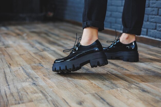 Hermosa mujer con piernas en ropa de moda elegante cuero charol negro zapatos con cordones closeup Imagen de mujer en estilo primavera