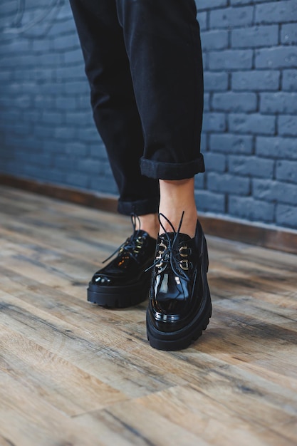Hermosa mujer con piernas en ropa de moda elegante cuero charol negro zapatos con cordones closeup Imagen de mujer en estilo primavera