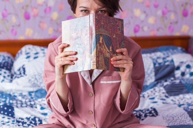 Hermosa mujer en pijama acogedor leyendo un libro