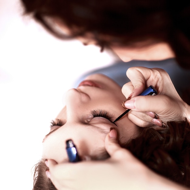 Hermosa mujer con pincel de maquillaje cerca de su rostro sobre un fondo blanco.