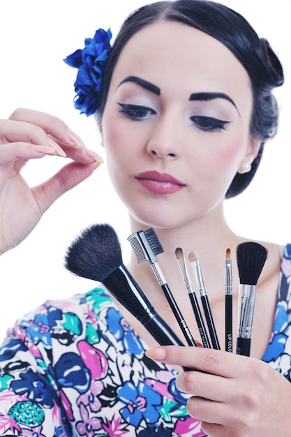 hermosa mujer pinup joven aplicar maquillaje y cosméticos tratamiento de belleza aislado en blanco en el estudio