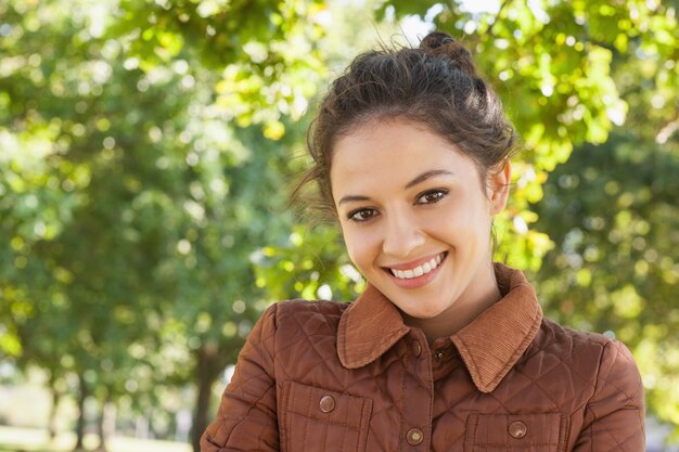 Hermosa mujer posando con un abrigo en un parque