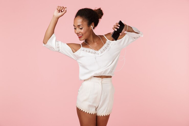 Foto hermosa mujer posando aislada sobre pared rosa escuchando música con auriculares bailando