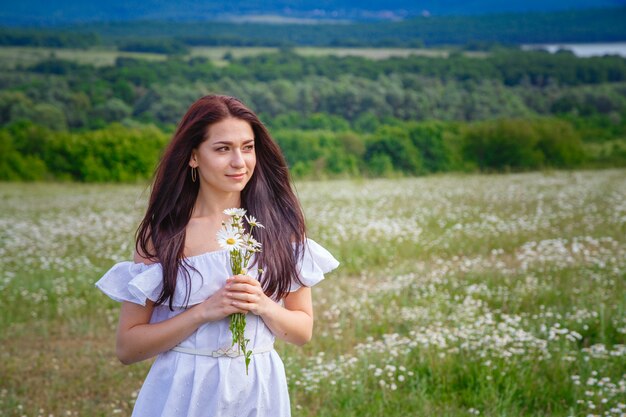 Hermosa mujer posando en un campo con margaritas