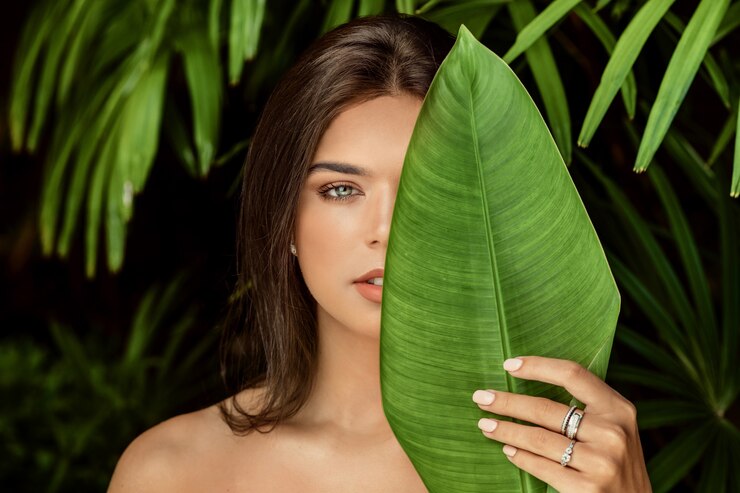 Foto hermosa mujer posando cerca de hojas verdes