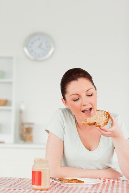 Hermosa mujer preparando una rebanada de pan y mermelada