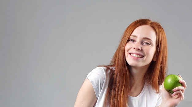 Hermosa mujer con primer plano de manzana verde. Una manzana verde en la mano de la niña.