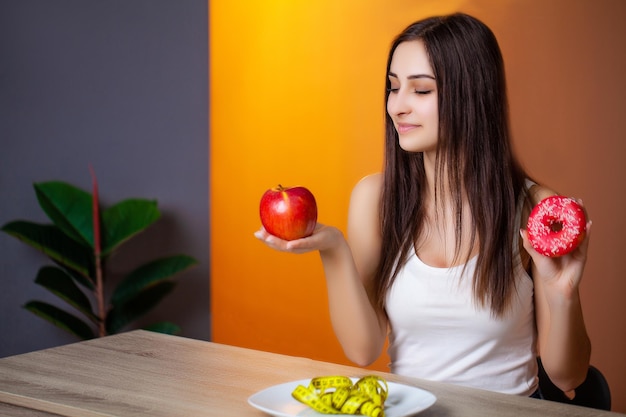 Hermosa mujer que elige entre alimentos útiles y dañinos.