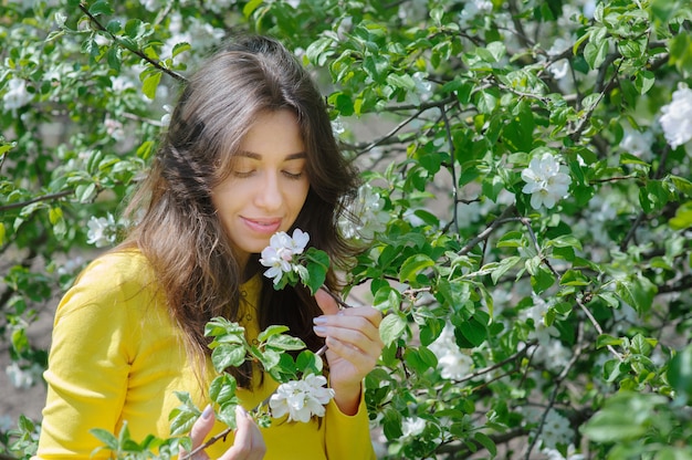 Hermosa mujer que huele una flor en el jardín de primavera