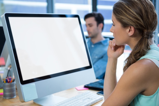 Foto hermosa mujer que trabaja en la pc de escritorio