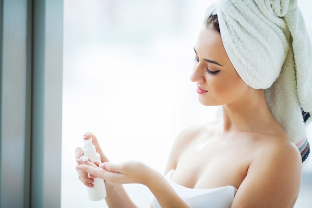 Foto una hermosa mujer que usa un producto para el cuidado de la piel, una crema hidratante o una loción, y skincare cuida su tez seca. crema hidratante en manos femeninas.
