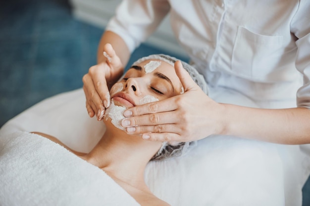 Hermosa mujer recibiendo masaje facial y tratamiento de spa en el salón de belleza cosmetología belleza proced