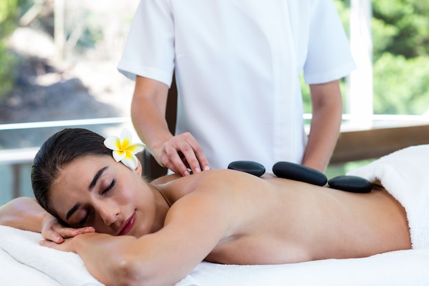 Hermosa mujer recibiendo masaje con piedras