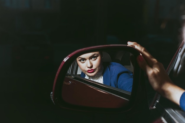 Hermosa mujer reflejada en el espejo del autoHermosa joven compra un auto en el salón del concesionario