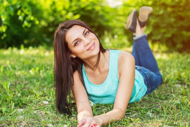 Hermosa mujer relajándose al aire libre en el césped luciendo feliz y sonriente