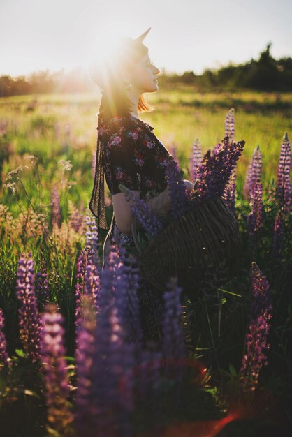 Foto hermosa mujer relajándose en el soleado campo de lupino con canasta rústica con flores momento tranquilo