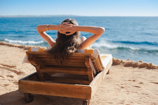 Hermosa mujer relajándose en una tumbona cerca de una lujosa playa de verano en el hotel Egypt. Concepto de tiempo para viajar