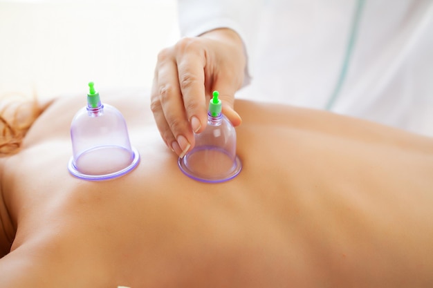 Foto hermosa mujer relajante en el salón de spa con masaje corporal al vacío.