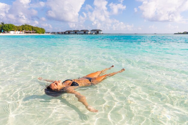 Hermosa mujer relajarse a flote en el resort tropical