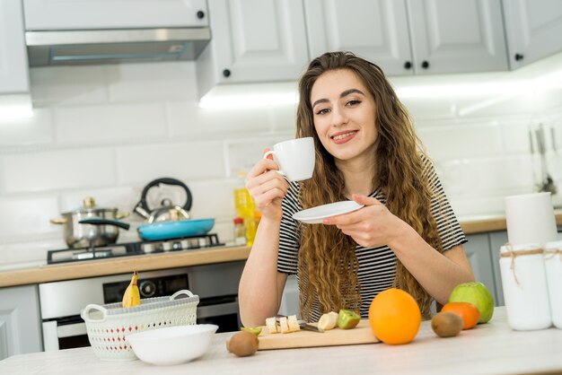 Hermosa mujer relajarse por la mañana en la cocina y beber disfrutar de un café. Cómodo ocio en casa.