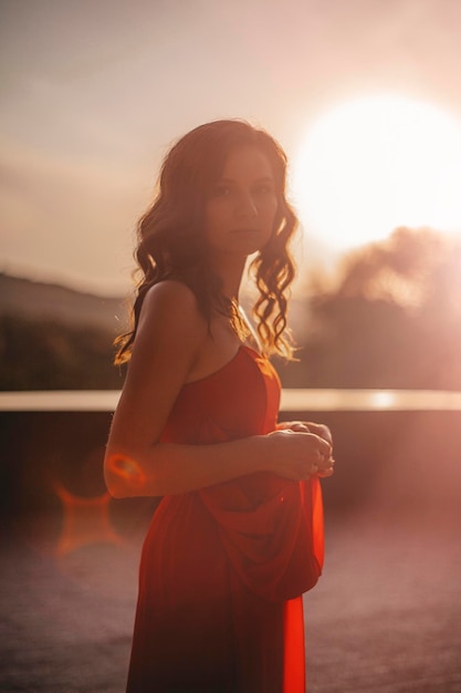 Hermosa mujer en retrato de puesta de sol de vestido rojo